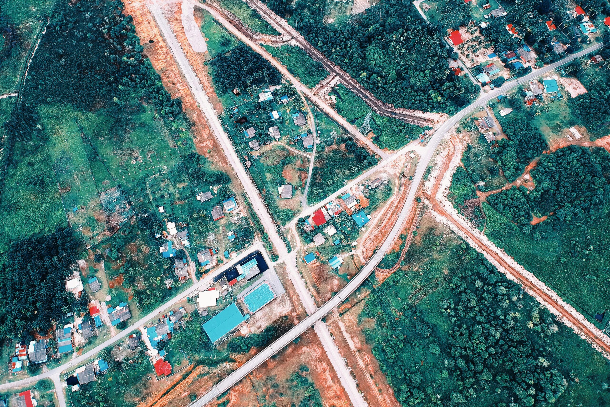 A captivating aerial shot of a rural town with winding roads, houses, and lush greenery.